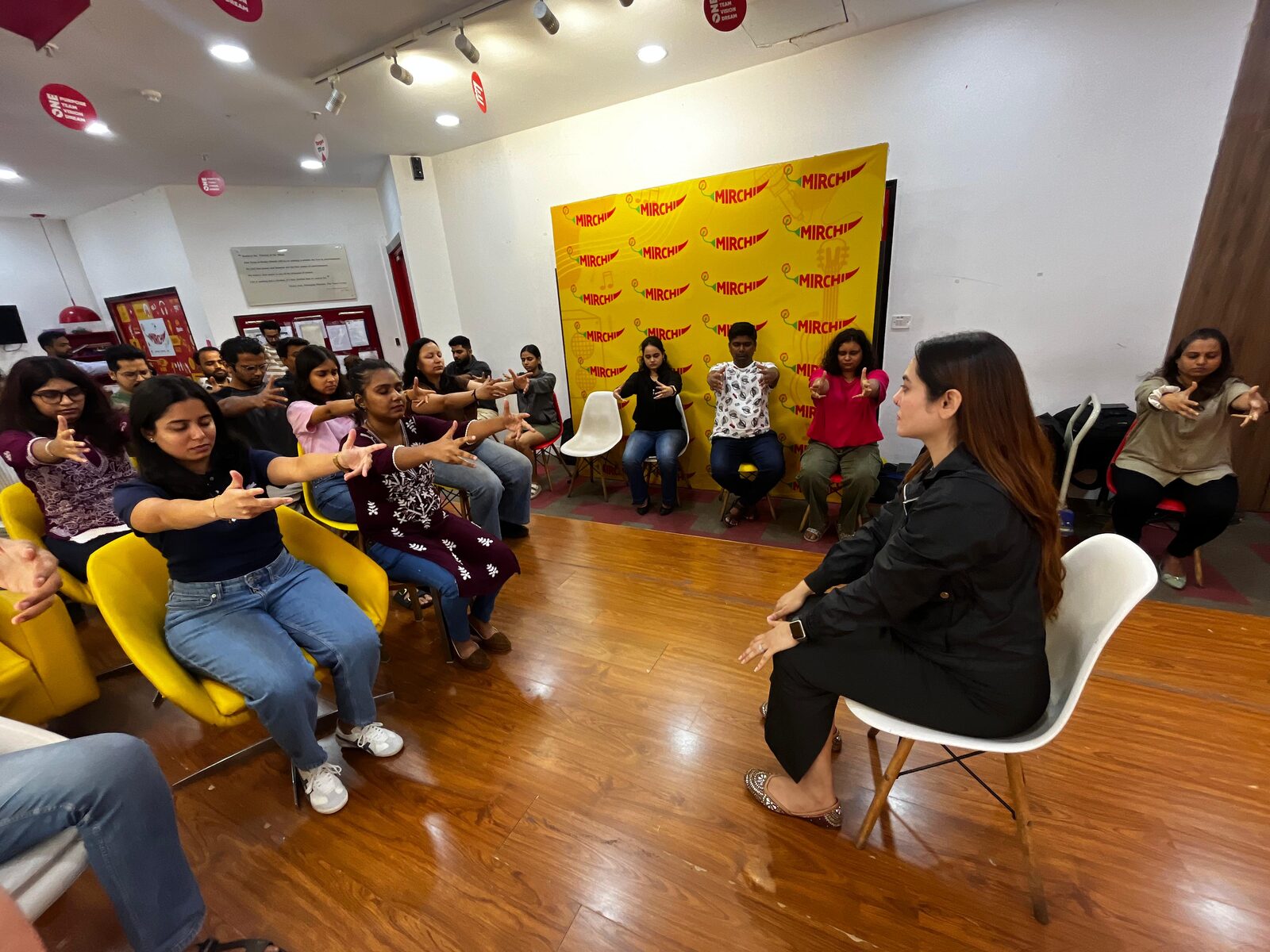 Vibha Jain leading a group workshop, seated facing a room of participants who are following a guided exercise.