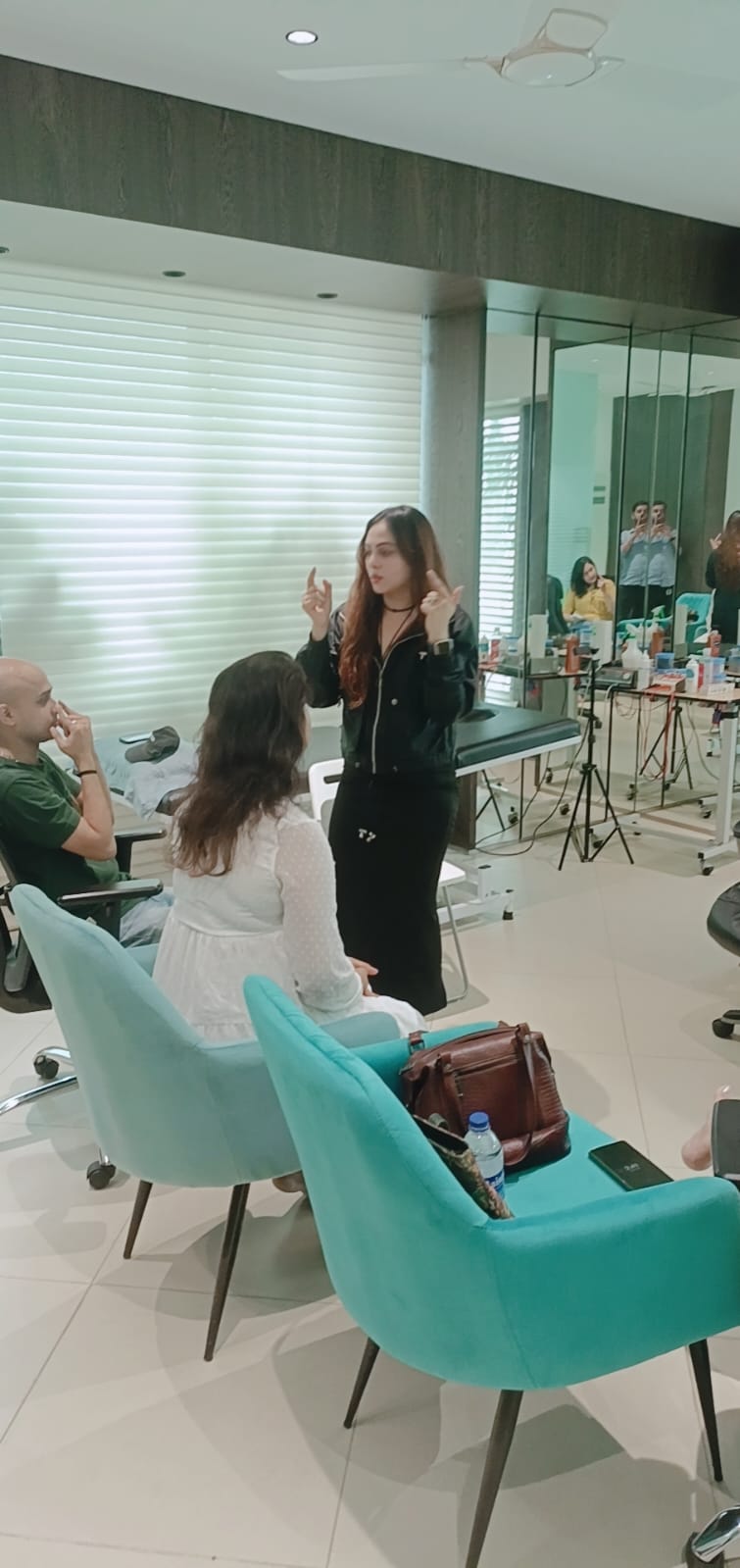 Vibha Jain stands and speaks with a small group of seated participants in a bright practice room.